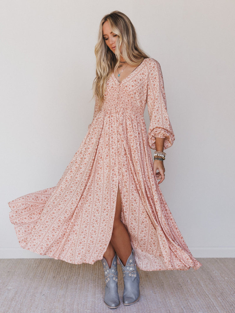 Woman wearing a flowing floral maxi dress in clay and cream
