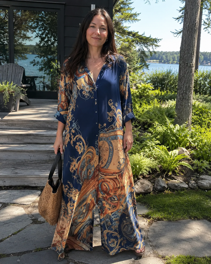 Customer photo: the navy dress worn on a wooden deck by the water, buttoned through, with a straw bag.