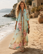 Woman wearing the Juliette mint-green maxi shirt dress on a beach, roses and butterflies printed across the skirt