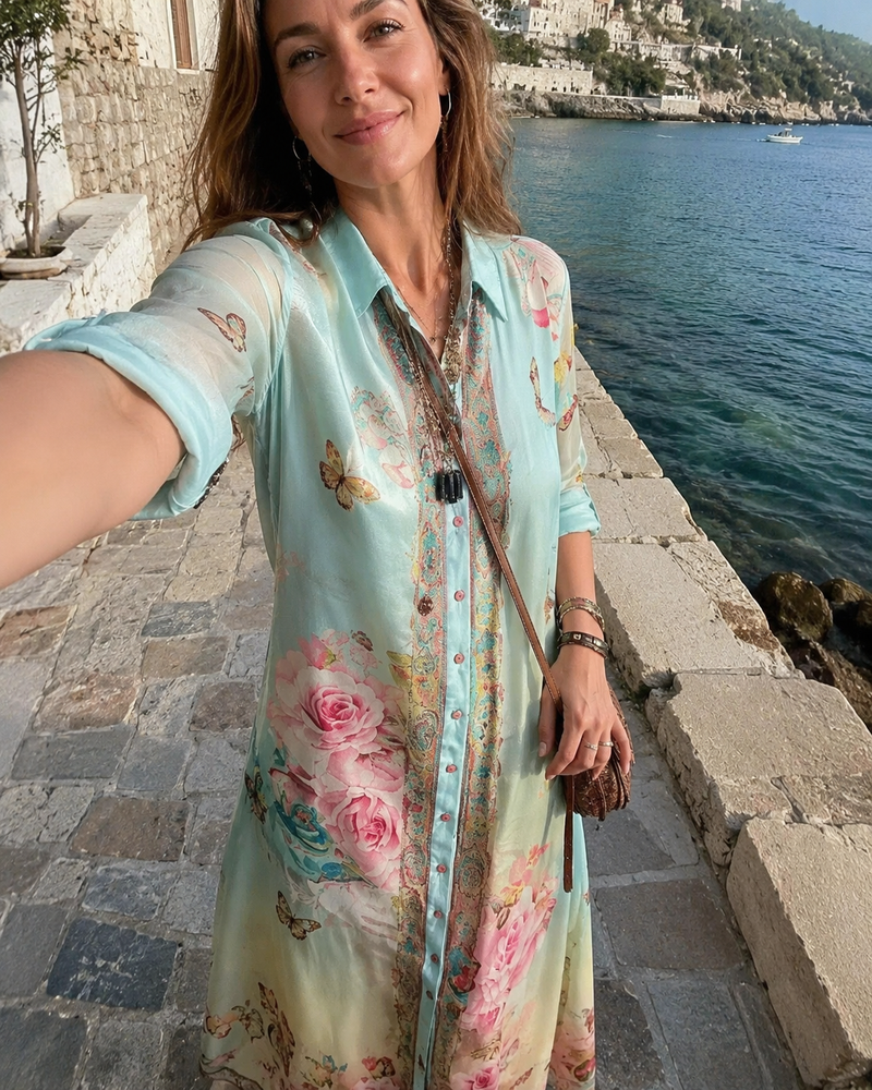 Customer photo: the Juliette shirt dress worn open over a swimsuit on a seaside promenade, sleeves rolled