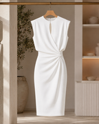 The Camille dress in white on a wooden hanger, showing the wrapped skirt and knot at the waist