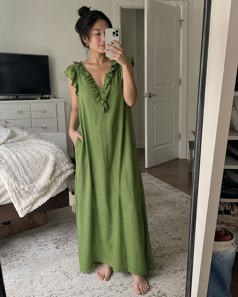 Customer photo: mirror selfie in the Rosalie dress in green, barefoot with the hem to the floor, hand in the pocket